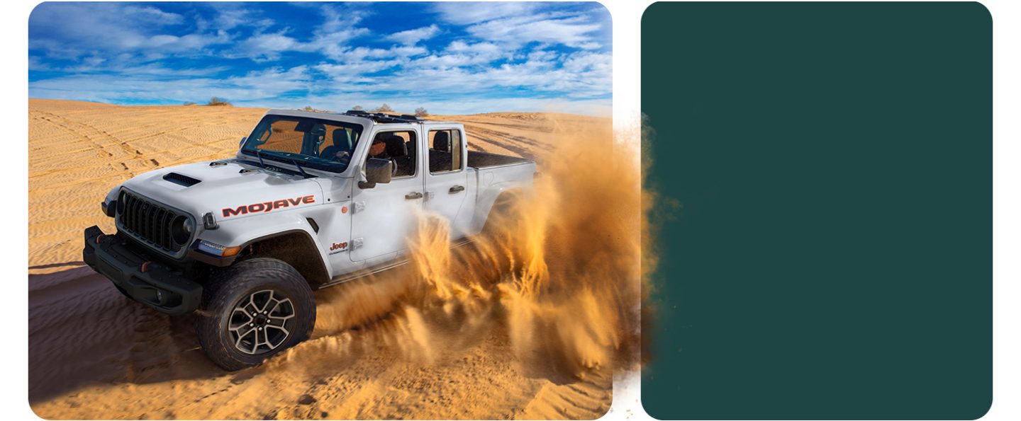 A white 2026 Jeep Gladiator Mojave X with its top removed, traveling through the desert, kicking up sand as it goes.