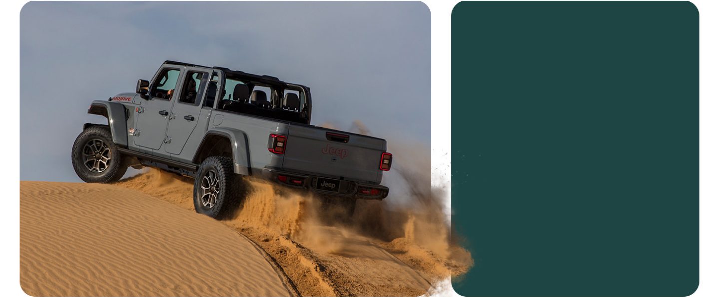 A gray 2026 Jeep Gladiator Mojave X ascending a sand hill in the desert.