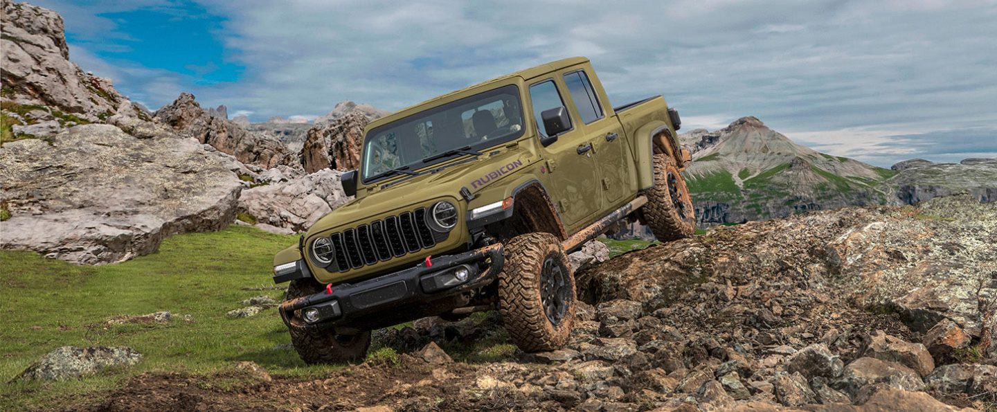 An olive green 2026 Jeep Gladiator Rubicon X descending a rugged, rocky trail off-road.
