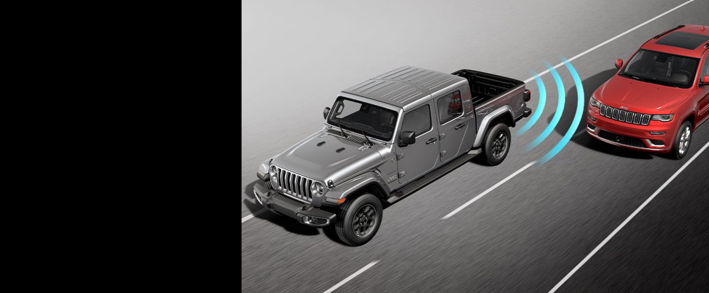 Illustrated sensor bars coming from the rear left of the 2022 Jeep Gladiator Overland, detecting an approaching vehicle in the next lane over.