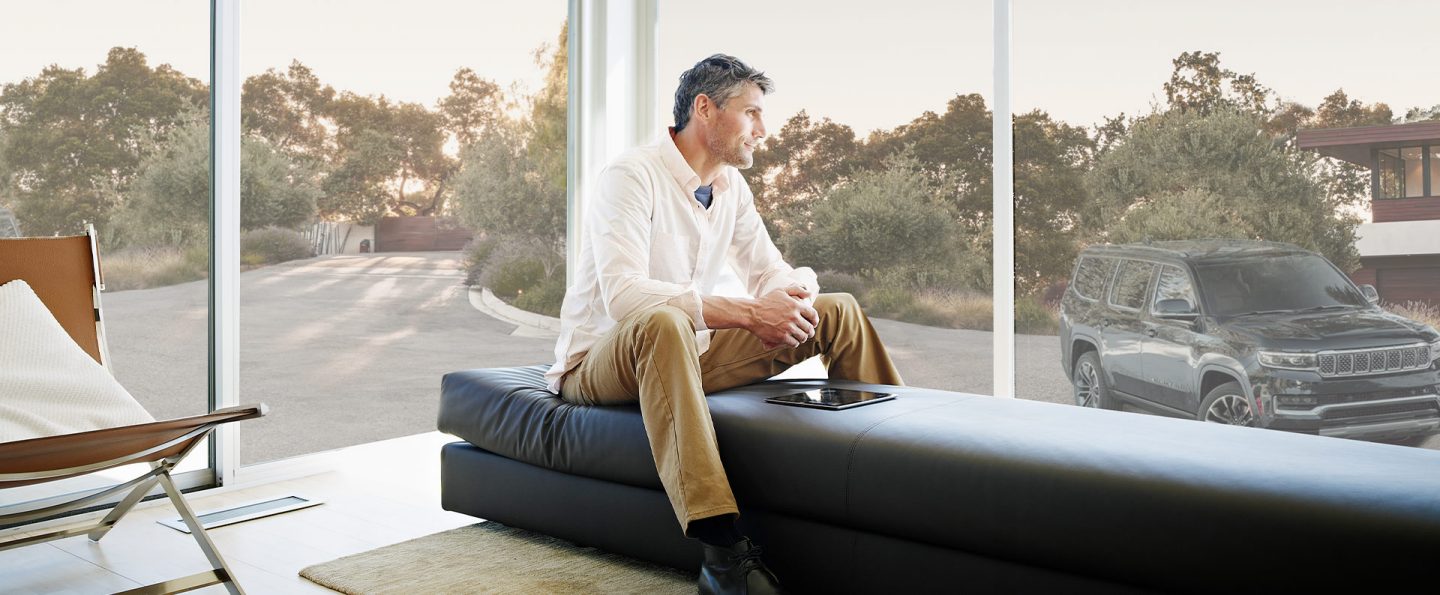 A man with a tablet in front of him looking out the window at a 2022 Wagoneer.